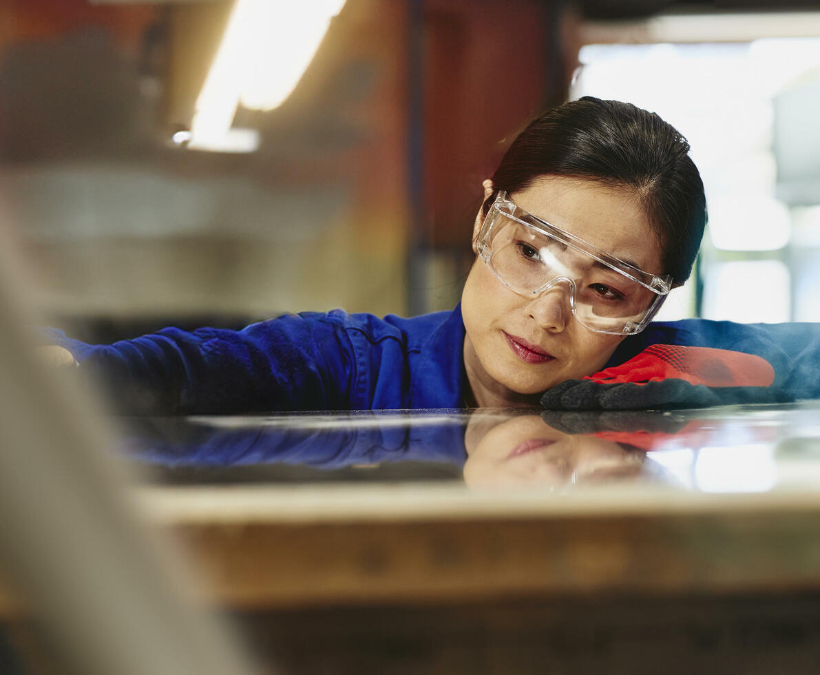 Womale wearing safety glasses and gloves watching a process closely.
 Womale wearing safety glasses and gloves watching a process closely.
