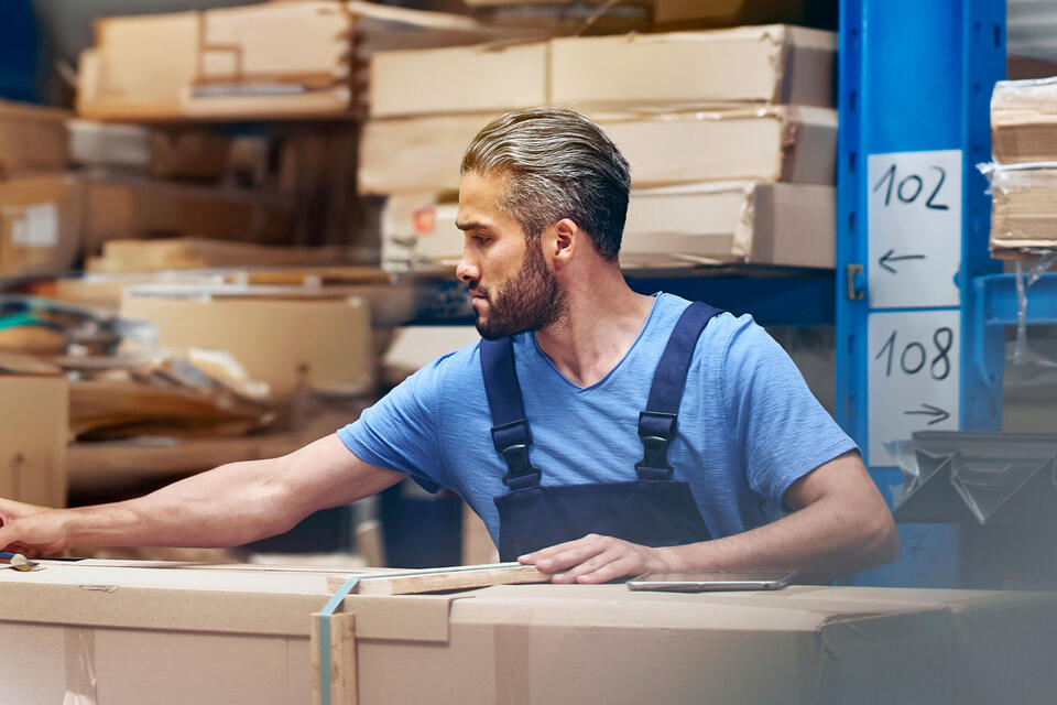 Randstad Operational Lager & Logistik male busy with parcels in a distribution center/warehouse.
