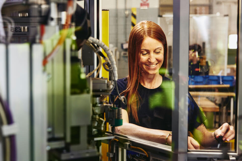Randstad Operational Produktion Smiling female operating a machine on a production site