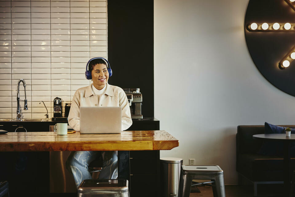 Man with headphones working on laptop at a table in a cafe Man with headphones working on laptop at a table in a cafe